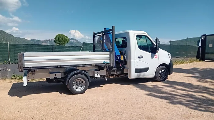 Autocarro bianco con cassone e gru blu per la movimentazione dei carichi